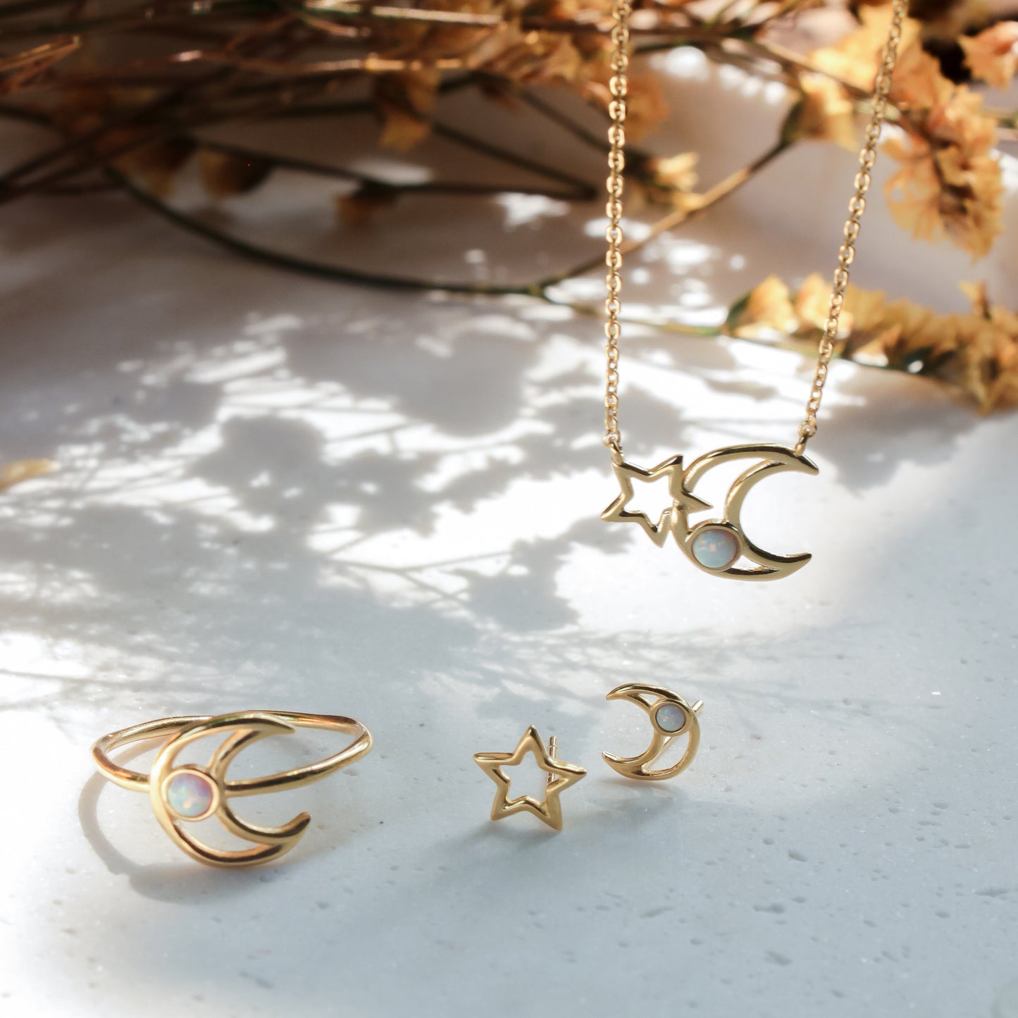 Gold jewelry set with rings, earrings, and a necklace on a textured surface.