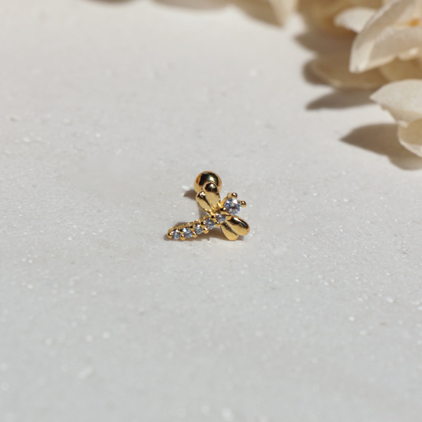 Gold cdragonfly earrings with small cubic zirconia on a light gray background