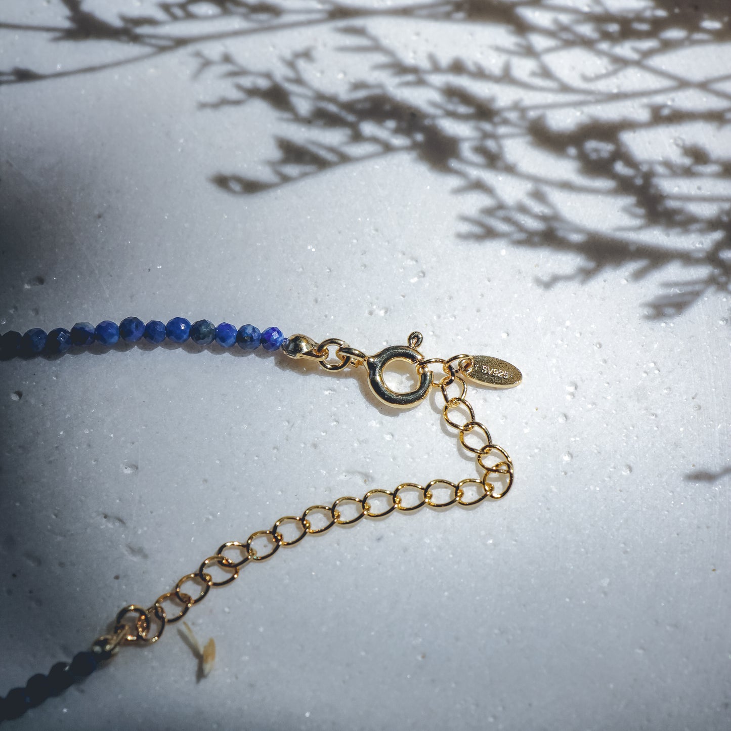 Gold bracelet with blue beads on a textured surface