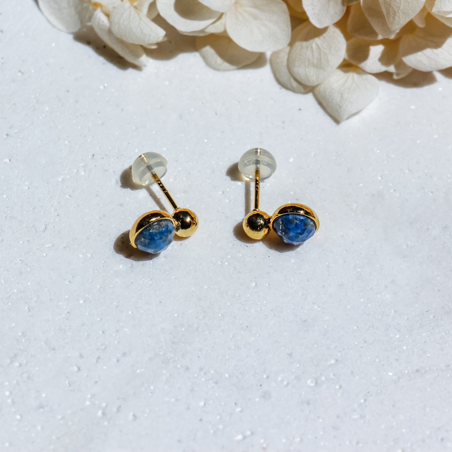 Gold earrings with blue stones on a white background