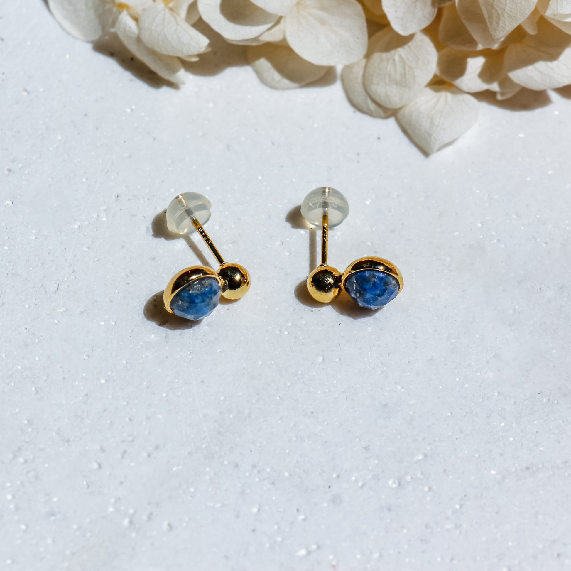 Gold earrings with blue stones on a white background
