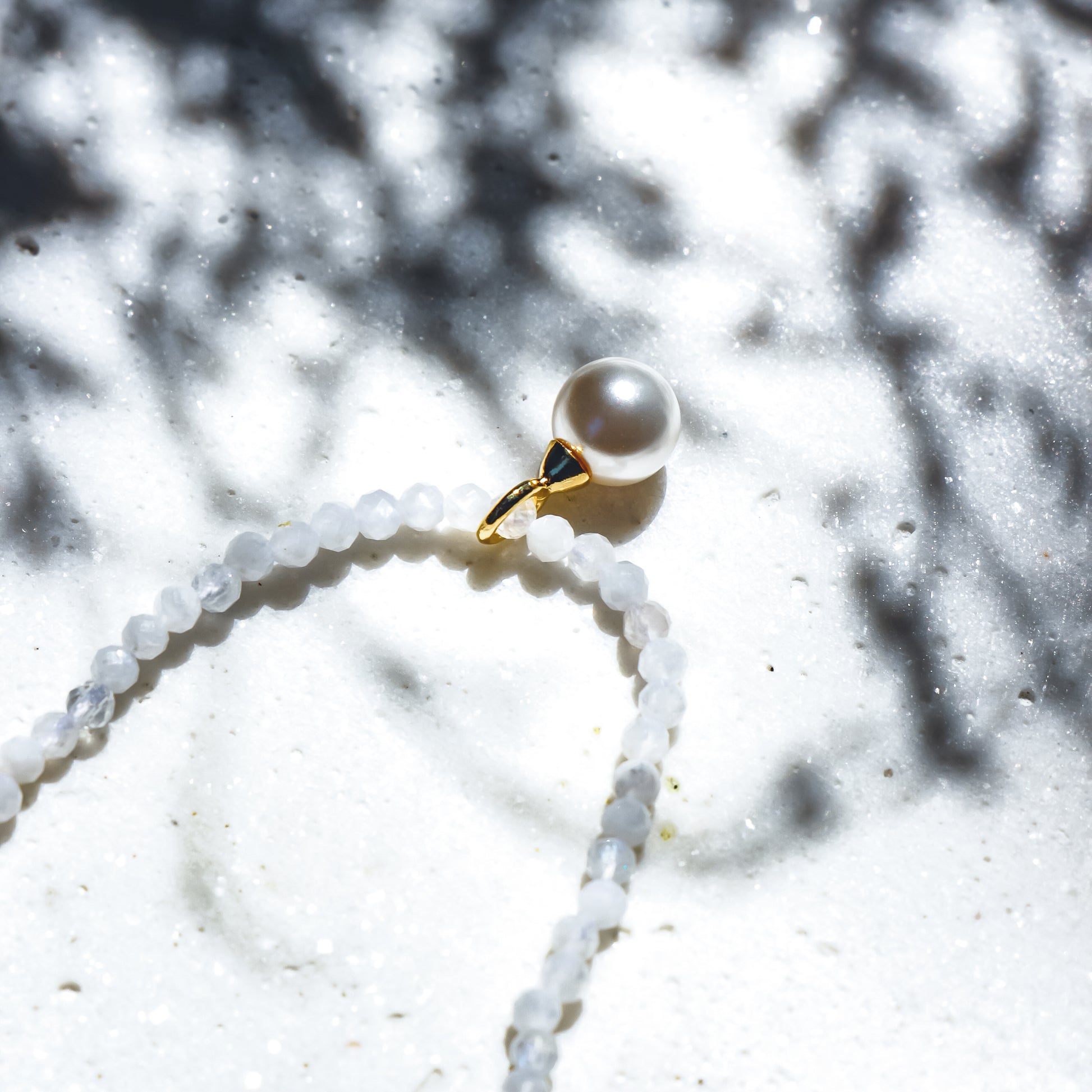 Pearl necklace with white stone on a white background