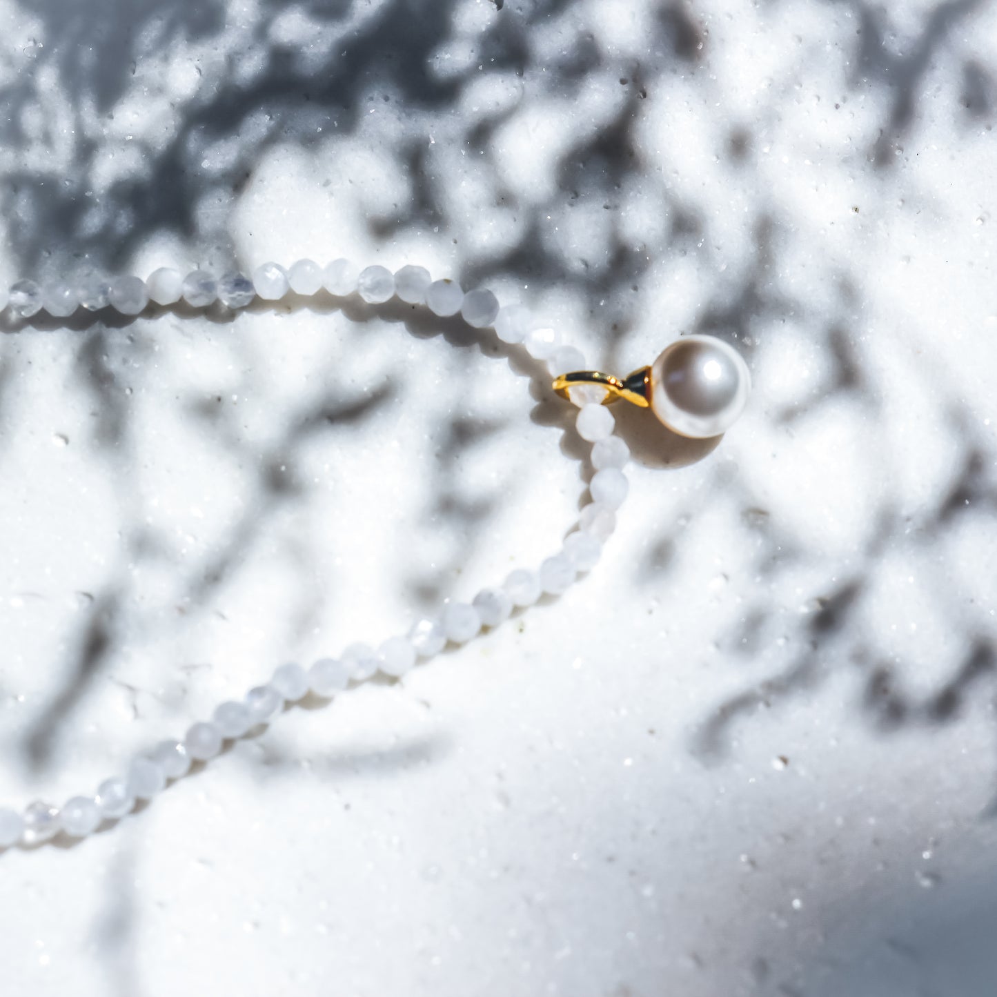 Pearl necklace with a gold clasp on a blurred natural background